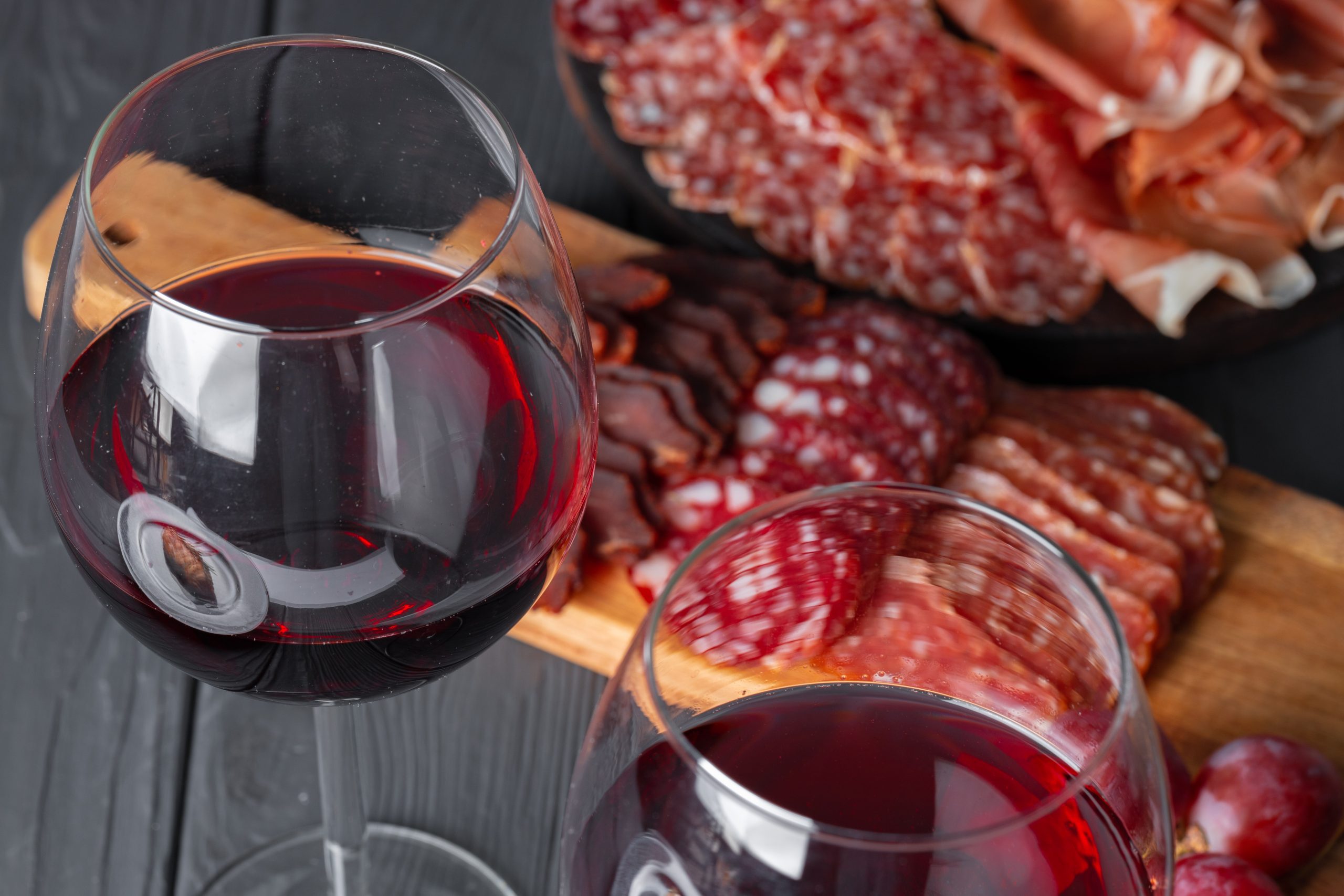 Wineglass with red wine and meat cuts board